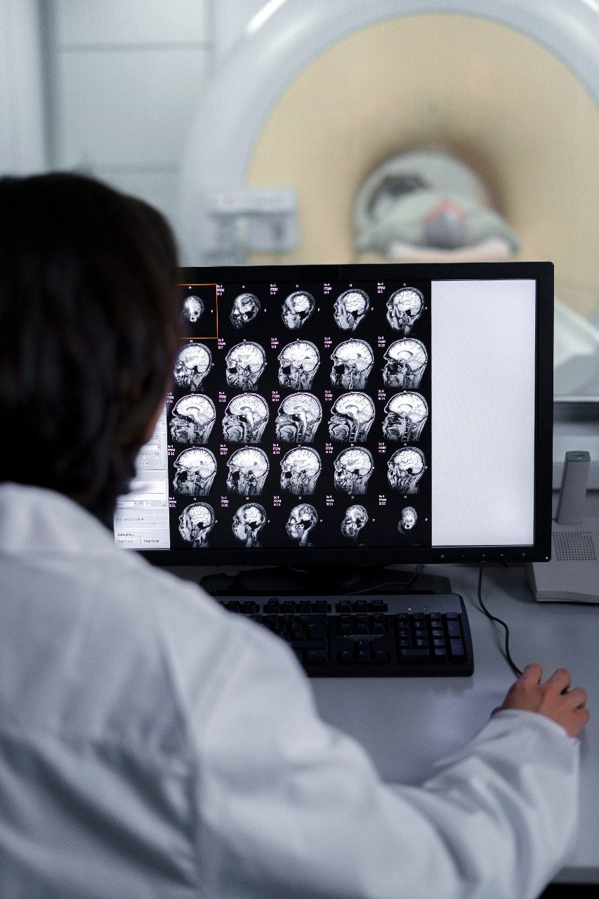 Technician reviewing brain scans on a computer monitor